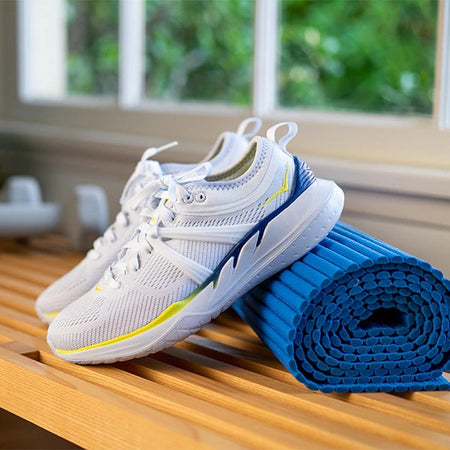 white hoka shoes leaning to blue yoga pad