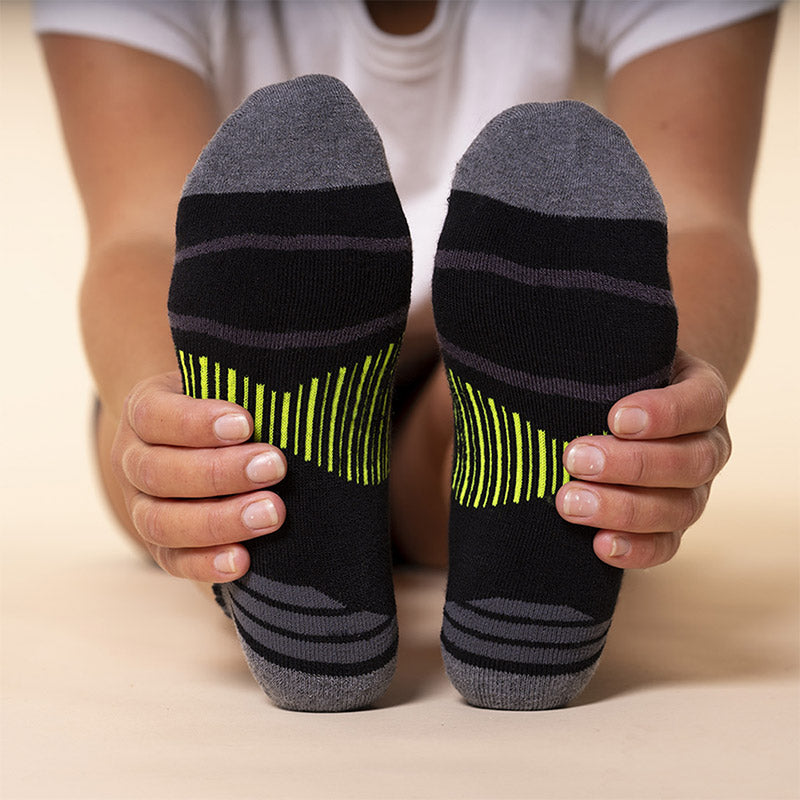 A person stretching towards their toes wearing Balega socks.